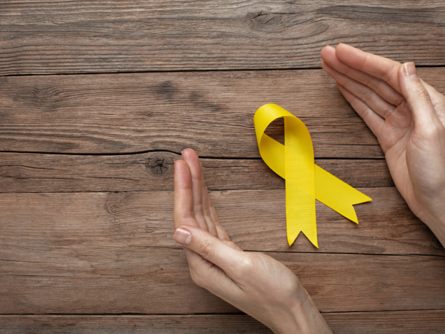 view-yellow-ribbon-with-human-hands-wooden-background